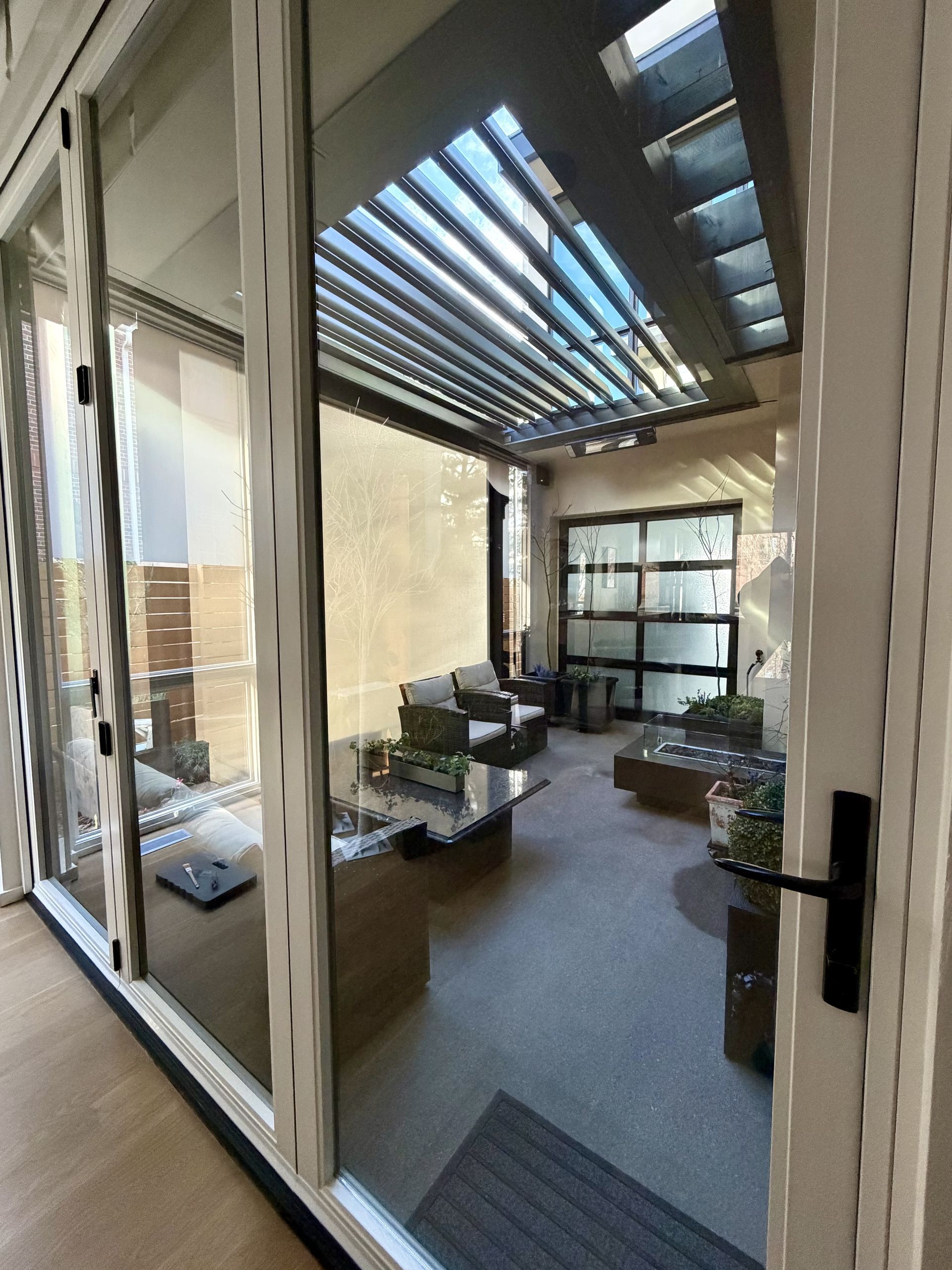 Modern outdoor patio with seating, skylight roof, and large windows overlooking a city view