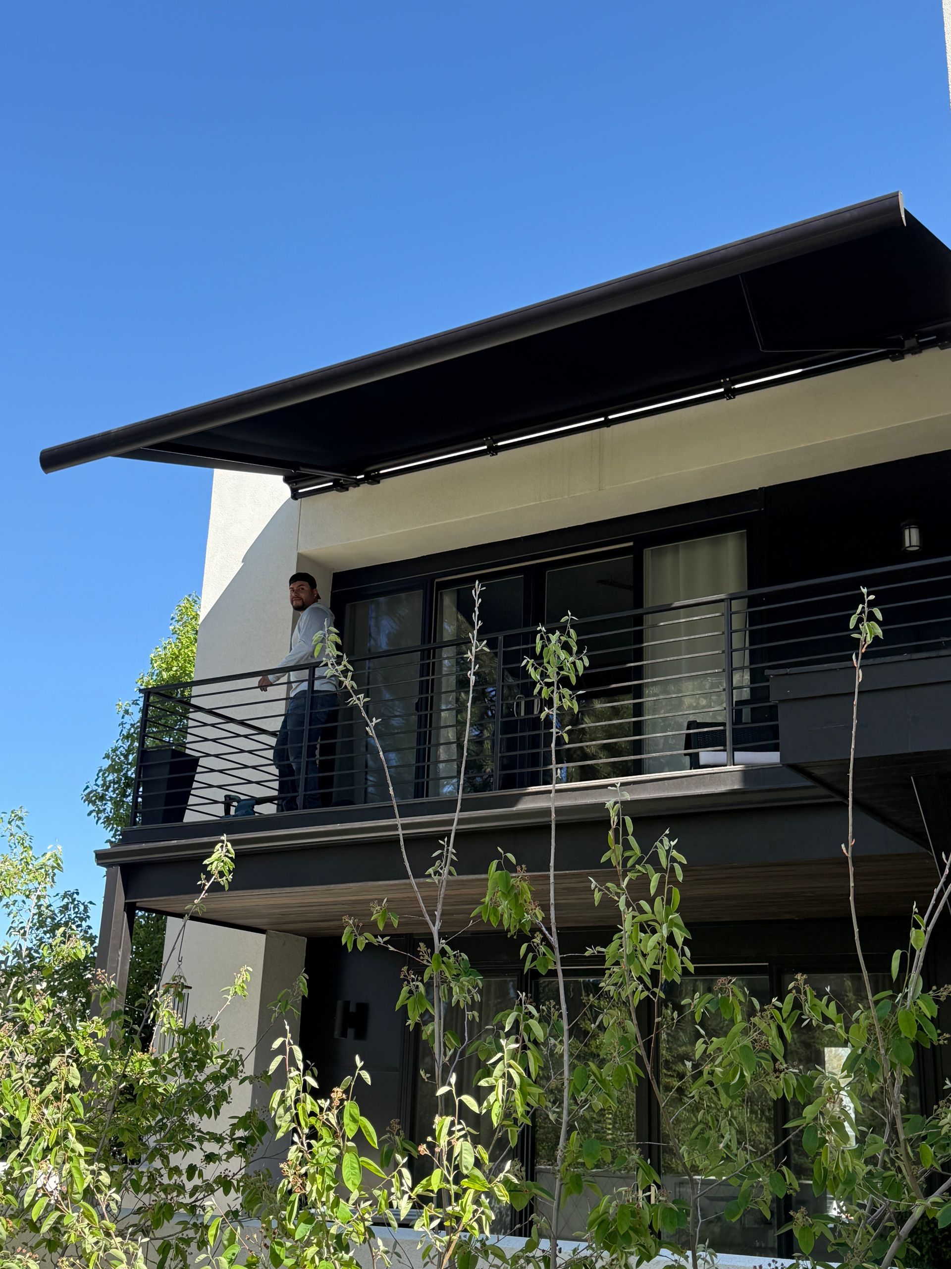 Modern house with dark balcony and large overhanging roof against a blue sky