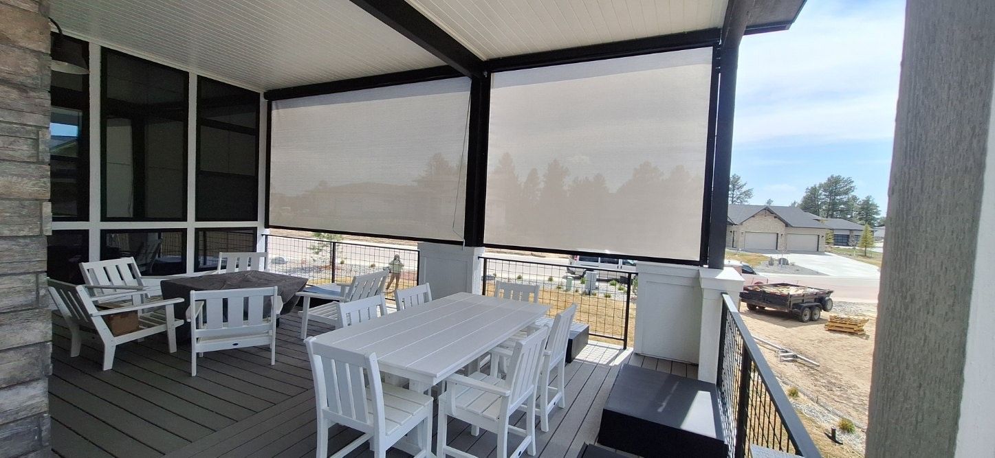 Covered patio with white outdoor dining furniture and a view of a yard and street beyond.
