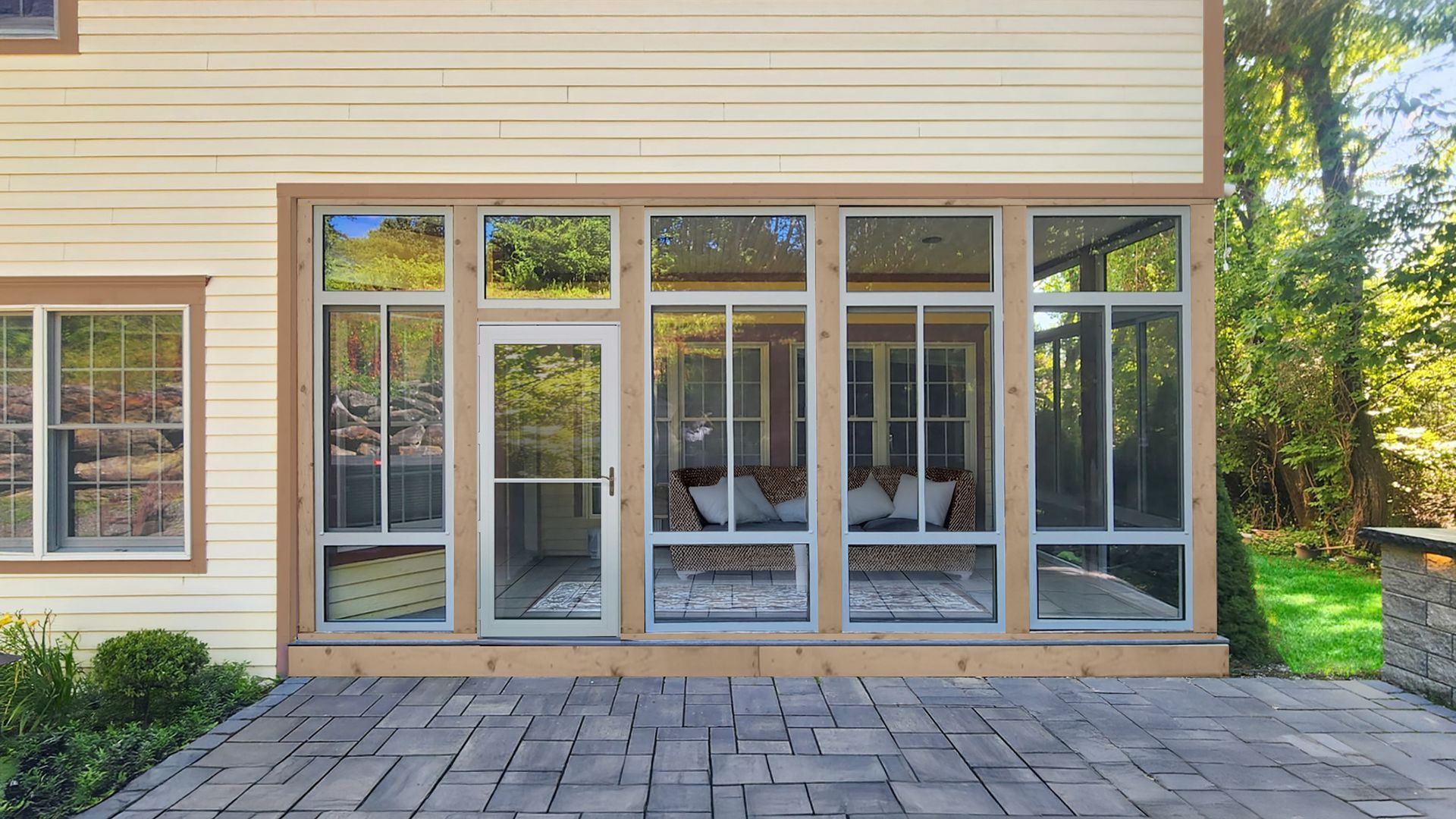 Exterior of a house with large glass patio doors and windows opening onto a stone patio