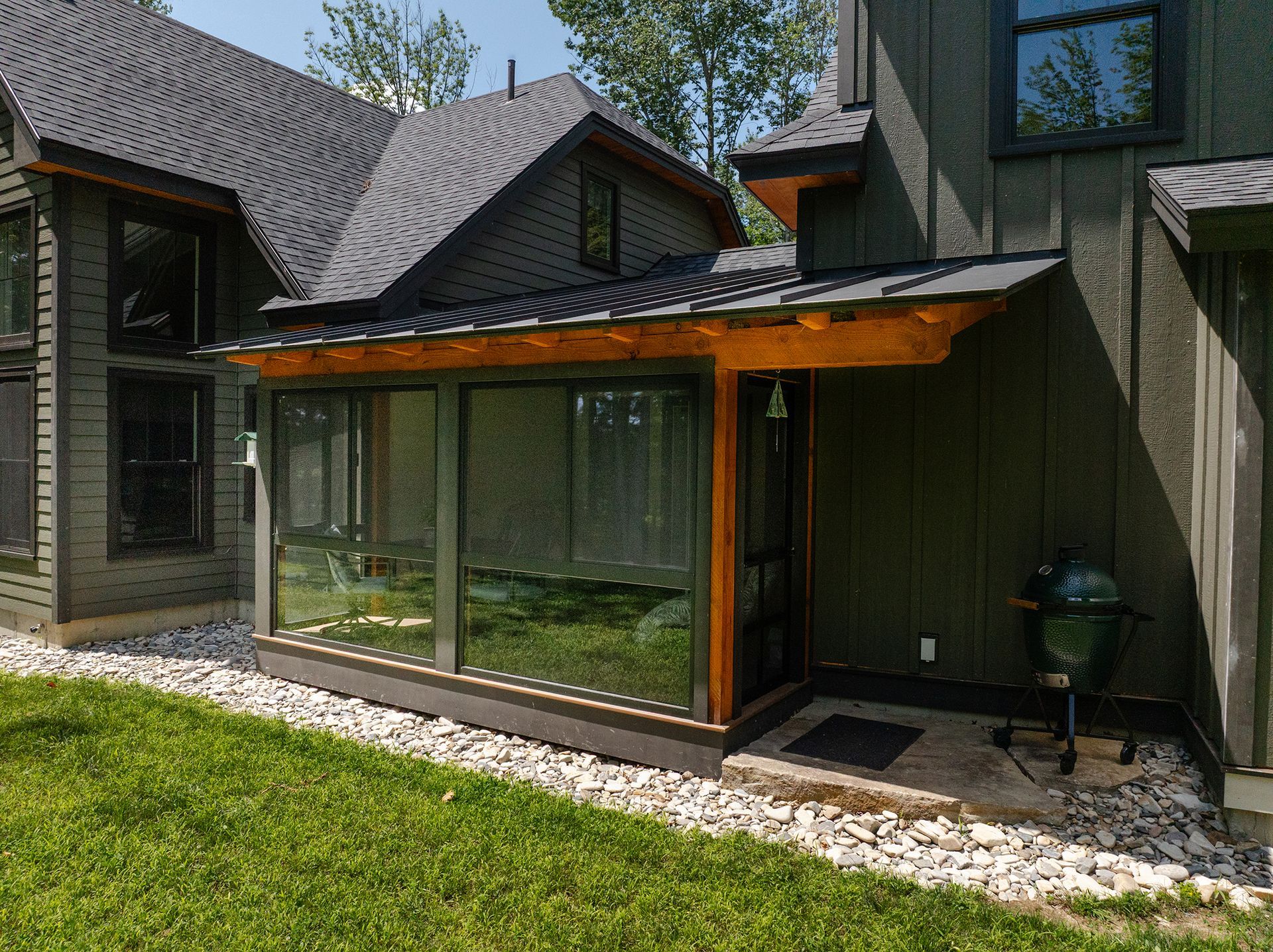 Modern house exterior with a large glass sunroom and green lawn in front