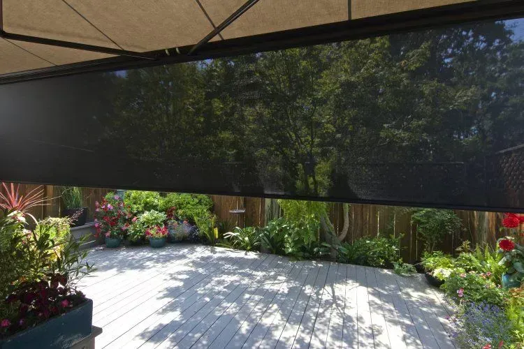 Shaded patio with a retractable awning overlooking a bright garden and patio stones