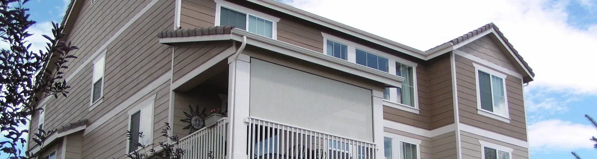 Corner view of a beige townhouse with white balcony railings under a blue sky