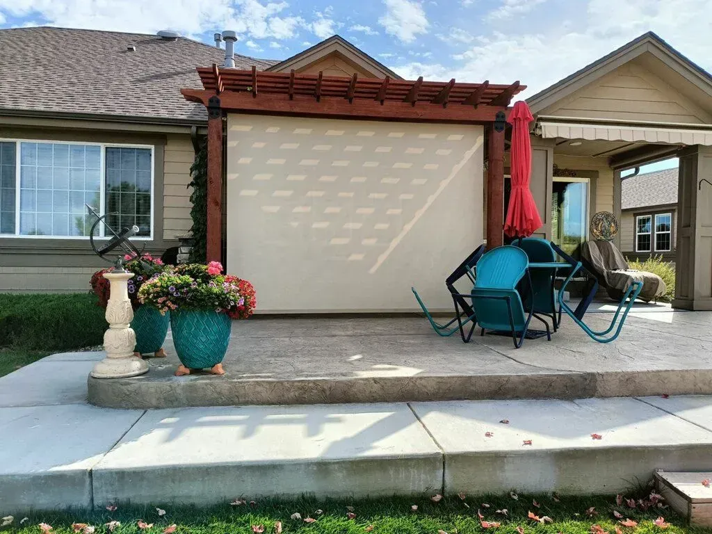 Front patio with blue chairs, red umbrella, potted flowers, and a beige garage door