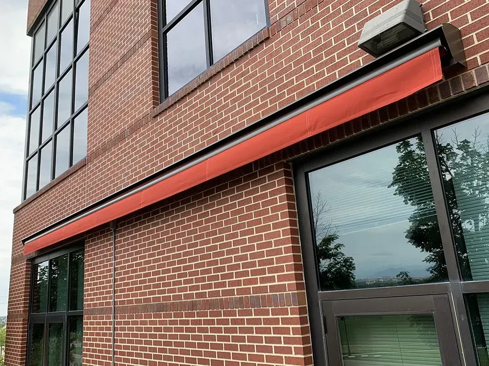 Brick building facade with black-framed windows and an orange awning over the storefront.