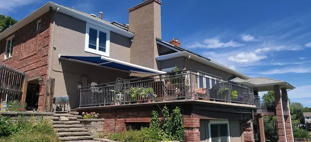 Brick house with multiple levels of decks and a blue sky.