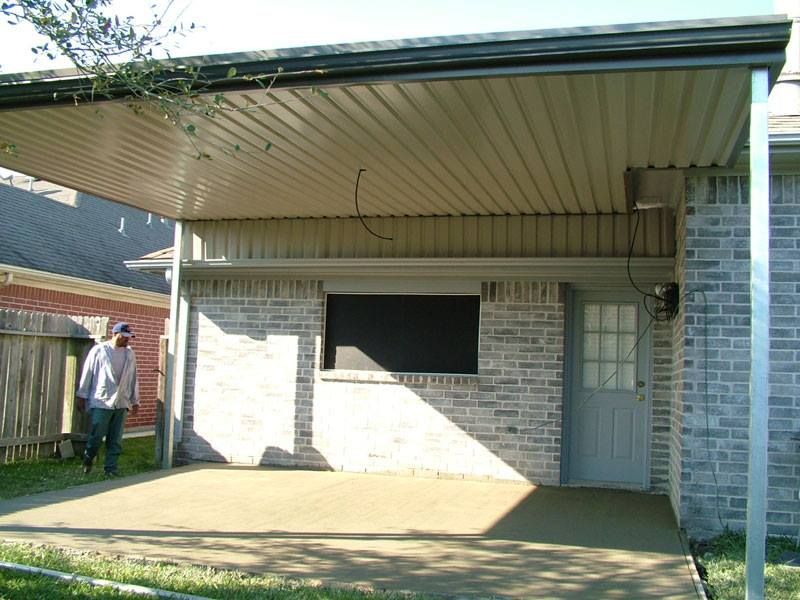 A man standing under a covered porch in front of a brick house