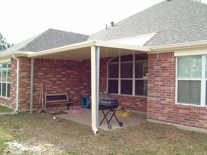 A brick house with a covered patio and a barbecue grill.