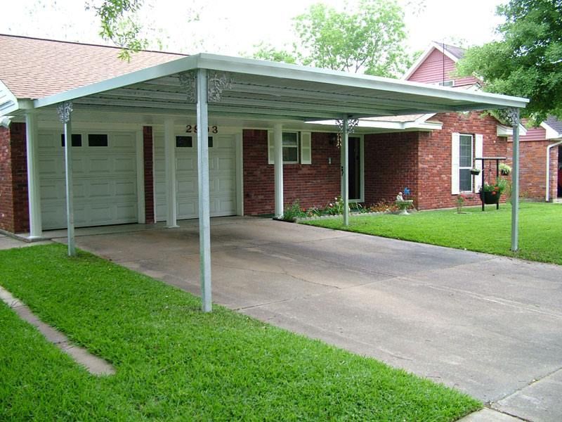 There is a carport in front of a brick house.