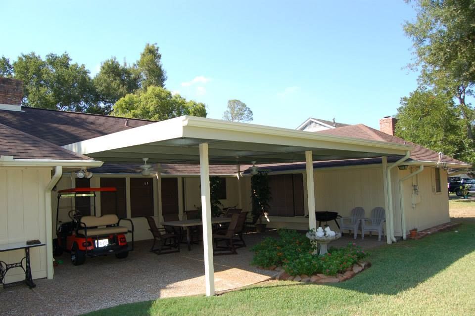 A golf cart is parked under a canopy in front of a house