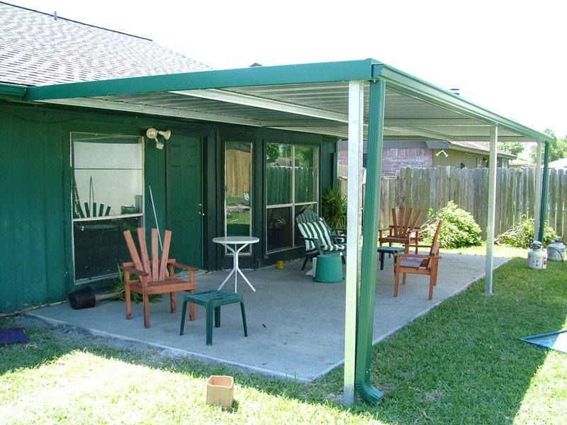 A green house with a covered patio with chairs and a table