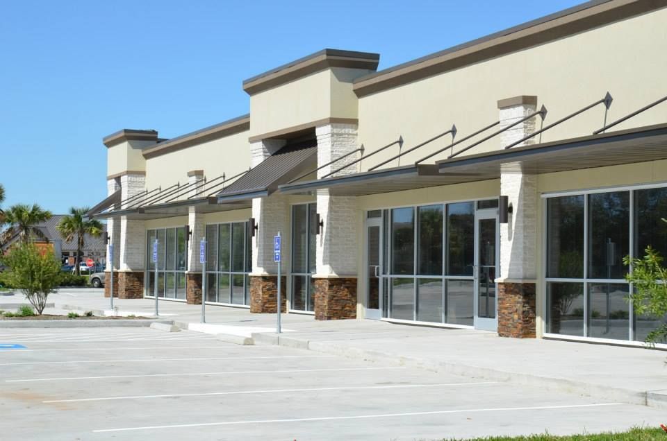 A row of empty buildings with a parking lot in front of them