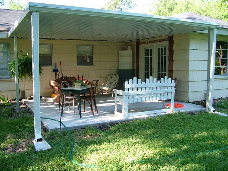 A patio with a table and chairs under a covered porch