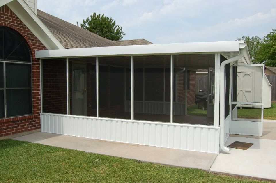 A screened in porch is attached to a brick house.