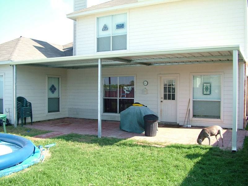 A white house with a patio and a trampoline in the backyard.