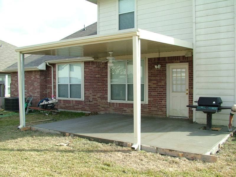 A house with a covered patio and a grill in front of it.