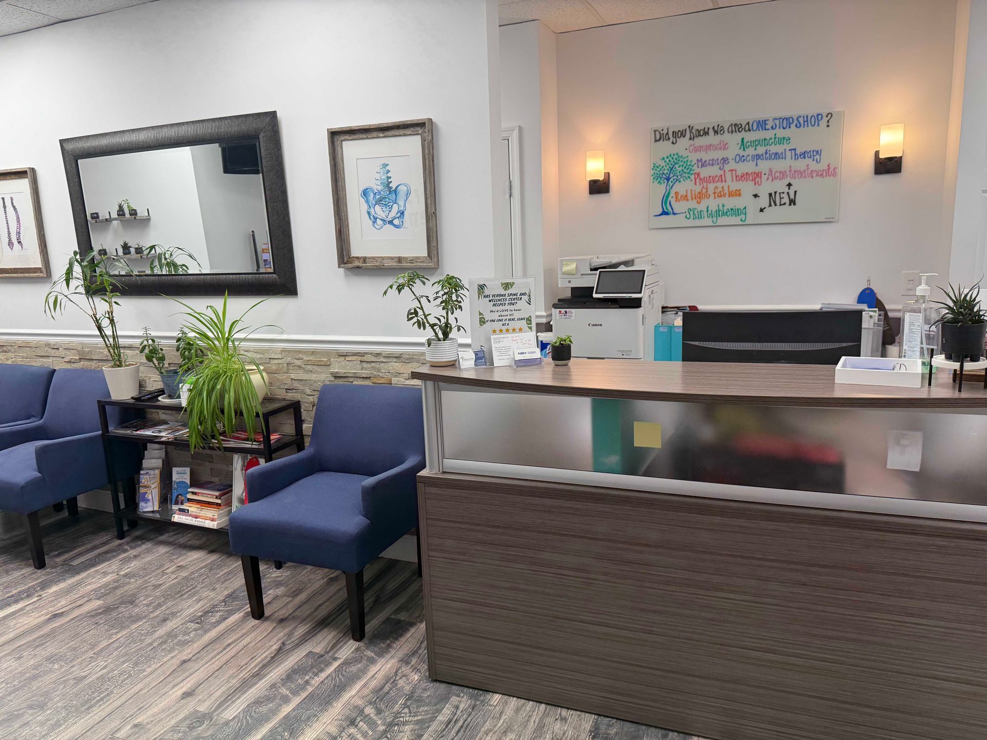Modern reception desk with blue chairs, plants, wall art, and a sign in a bright waiting area