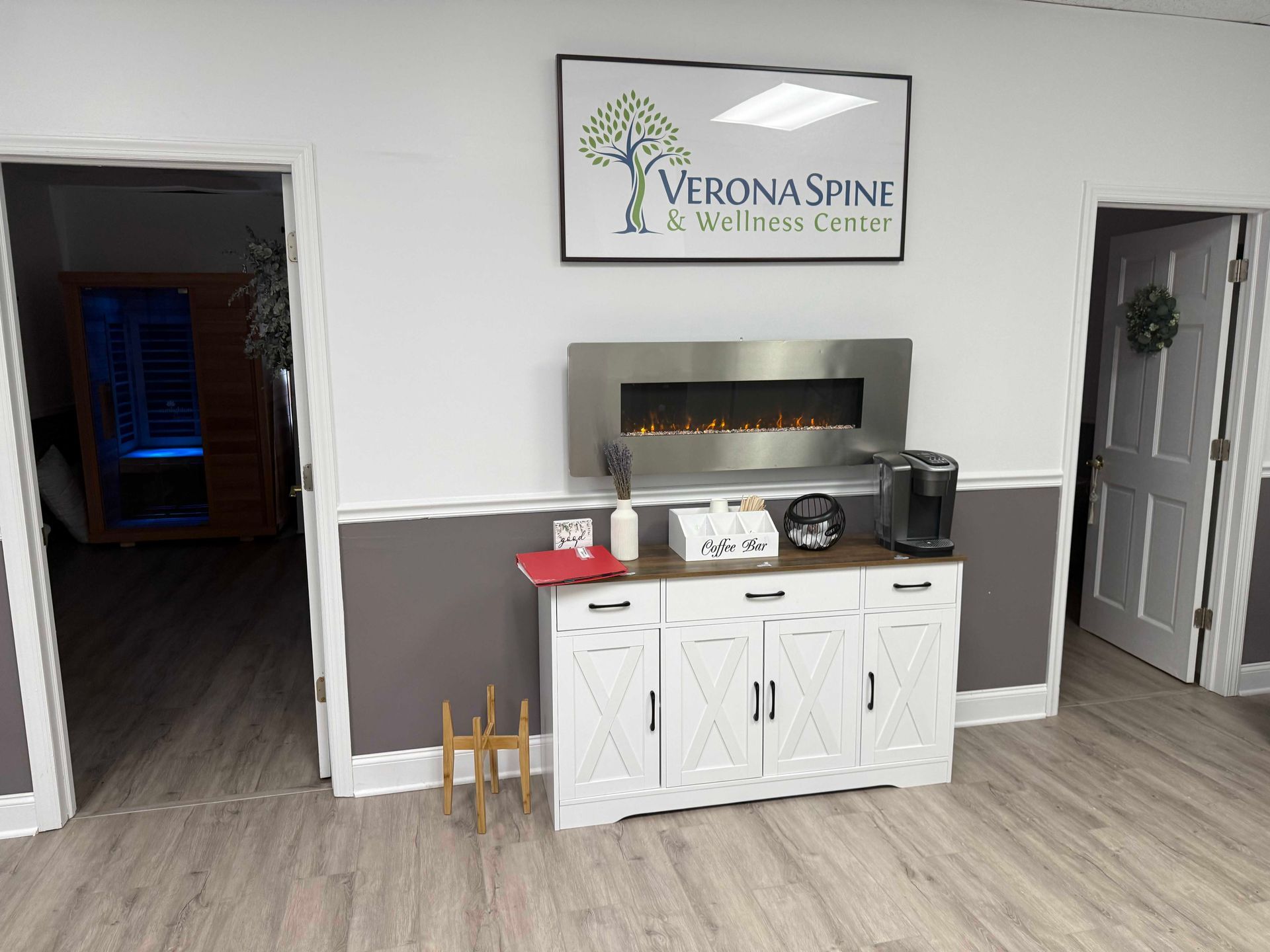 Reception area with Verona Spine sign, white cabinet, and doorway to hallway.