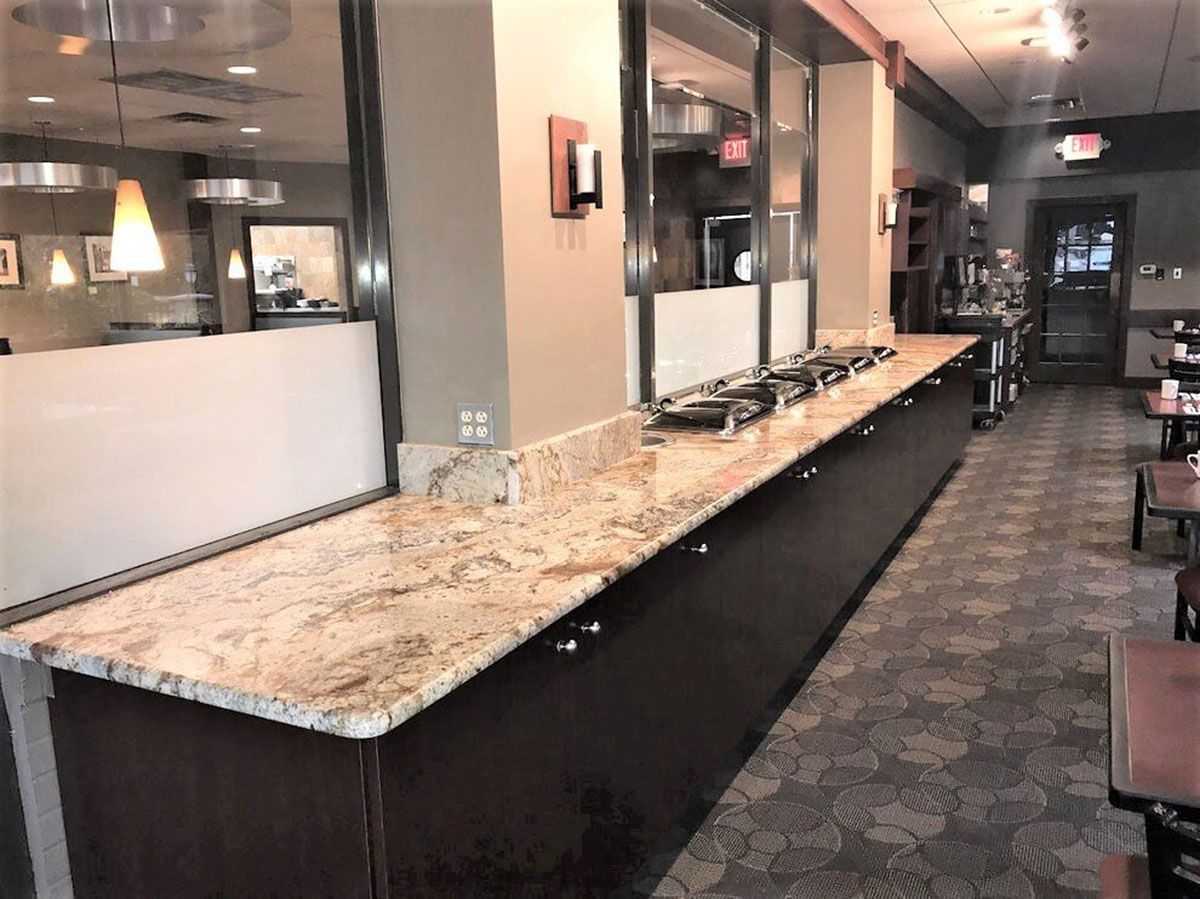 A long buffet countertop in a restaurant with tables and chairs