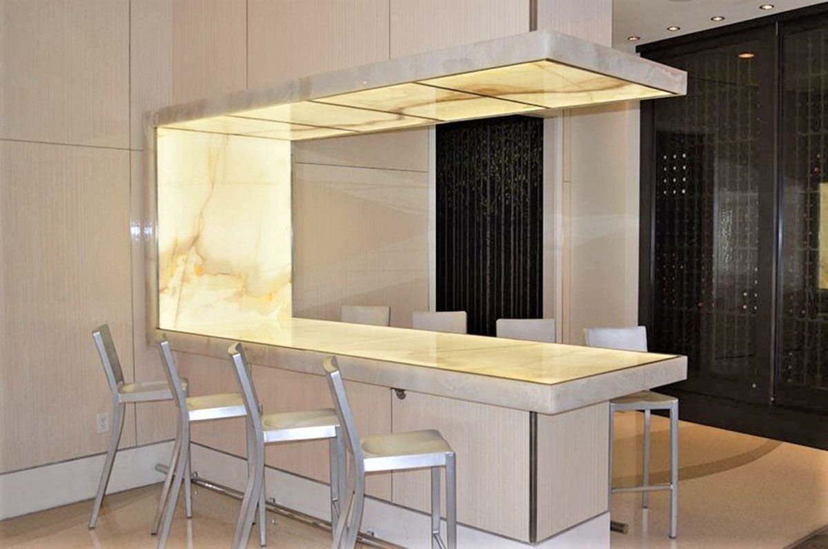 A kitchen with a bar and chairs and a marble countertop