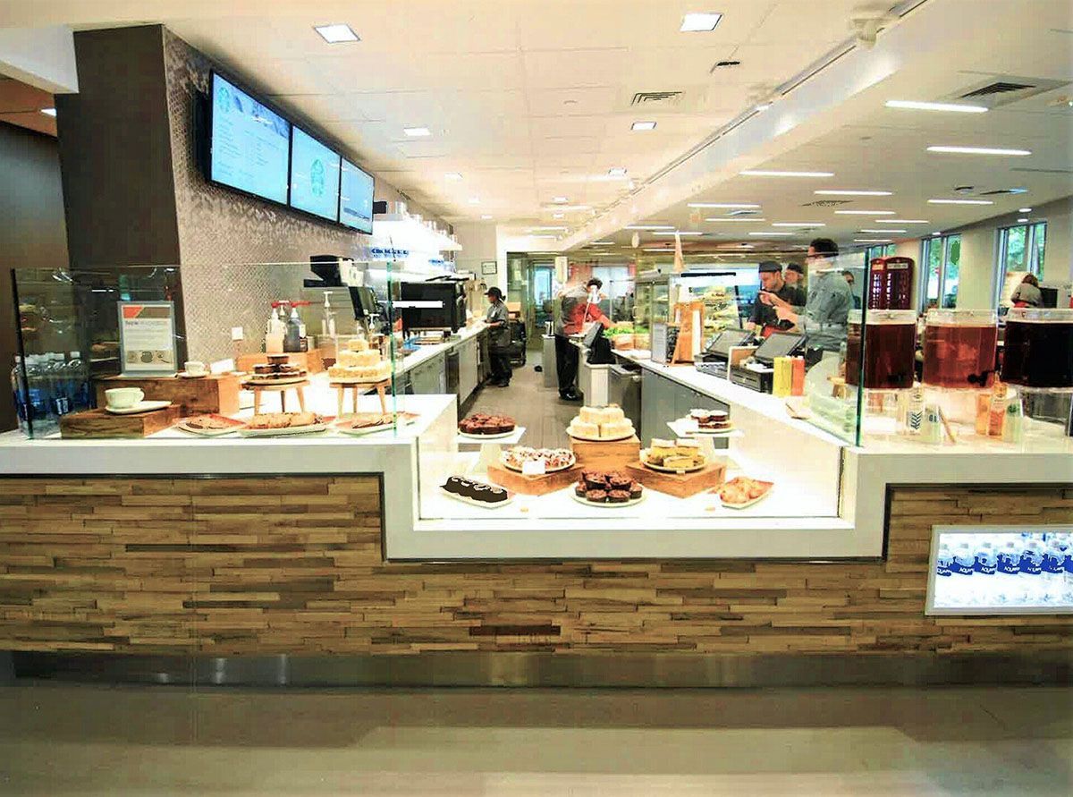 A buffet line in a restaurant with people standing in the background
