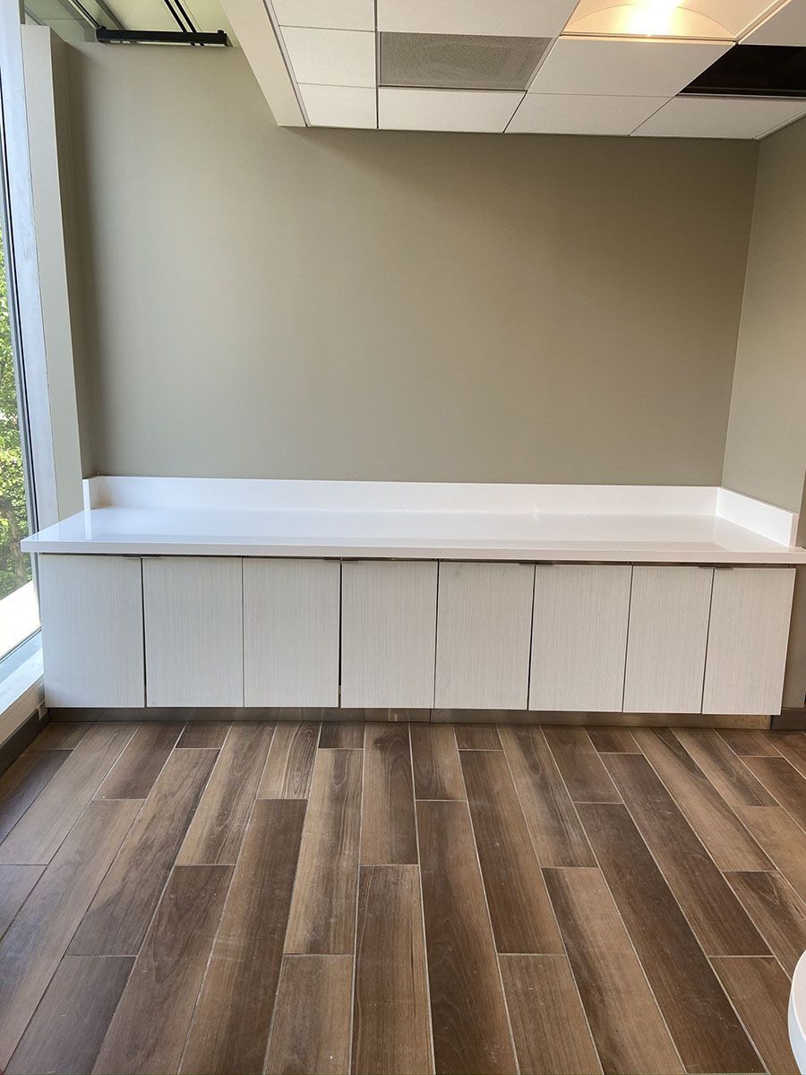A room with wooden floors, white countertop, and white cabinets