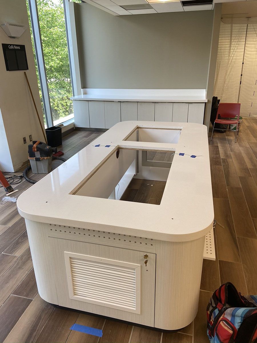 A long white table is sitting in a room next to a window