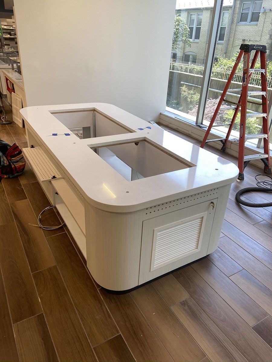 A large white table is sitting on a wooden floor next to a window