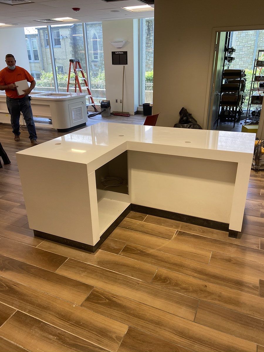 A man is standing next to a white counter in a room