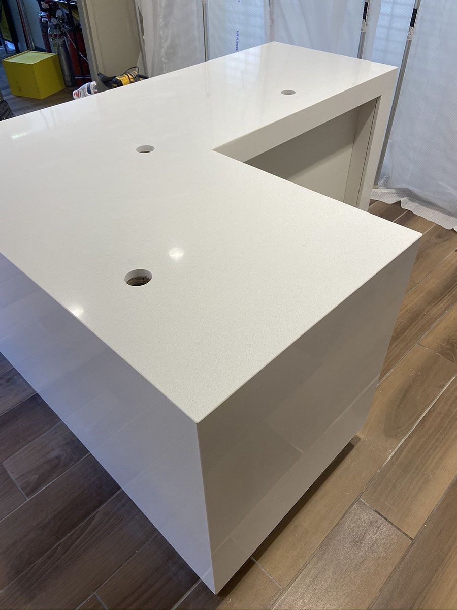 A white countertop with holes in it is sitting on a wooden floor