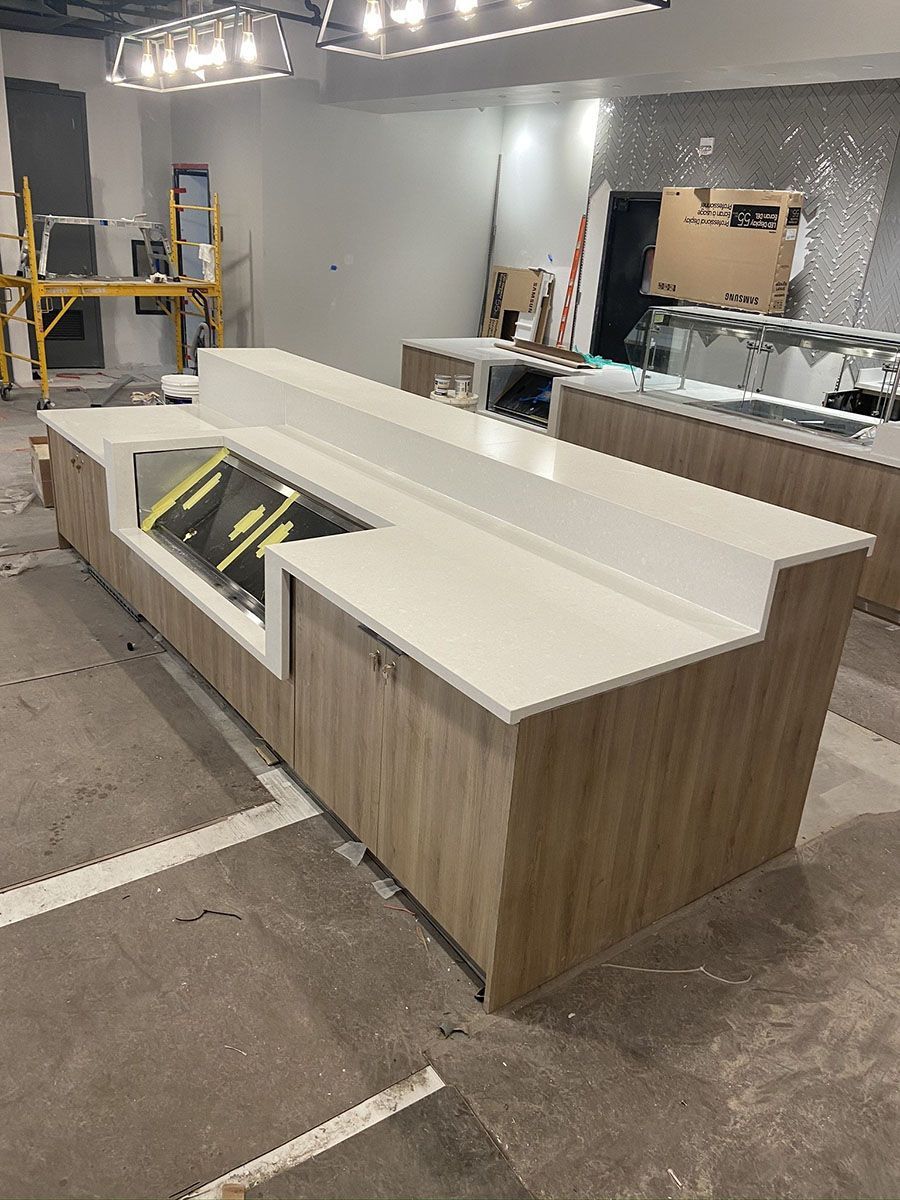 A kitchen under construction with a long counter and wooden cabinets
