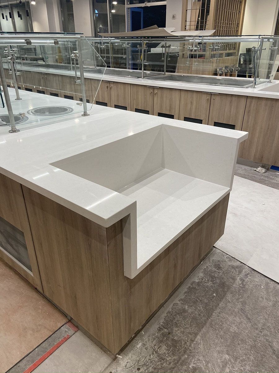 A kitchen with a white countertop and wooden cabinets