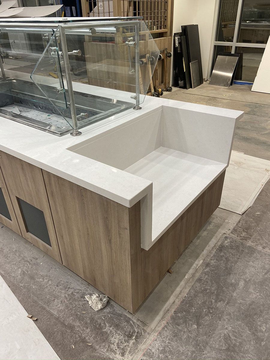 A wooden counter with a white countertop and a glass display case