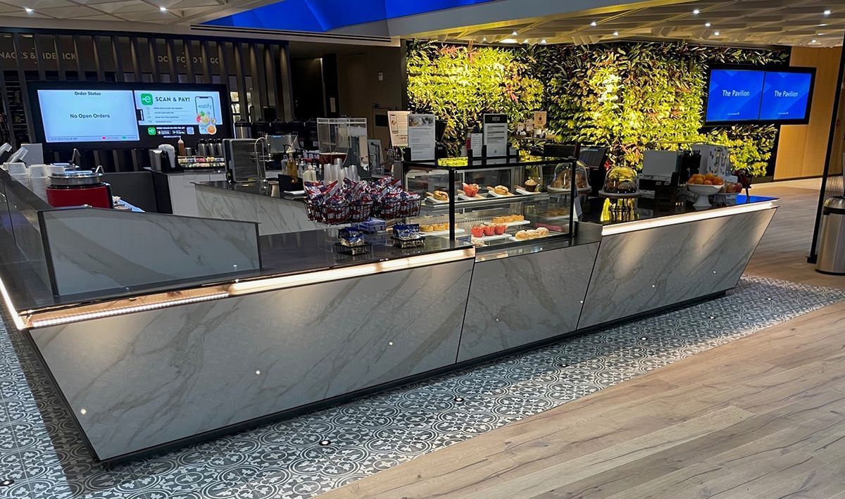 A restaurant with a long counter and a wall of flowers behind it