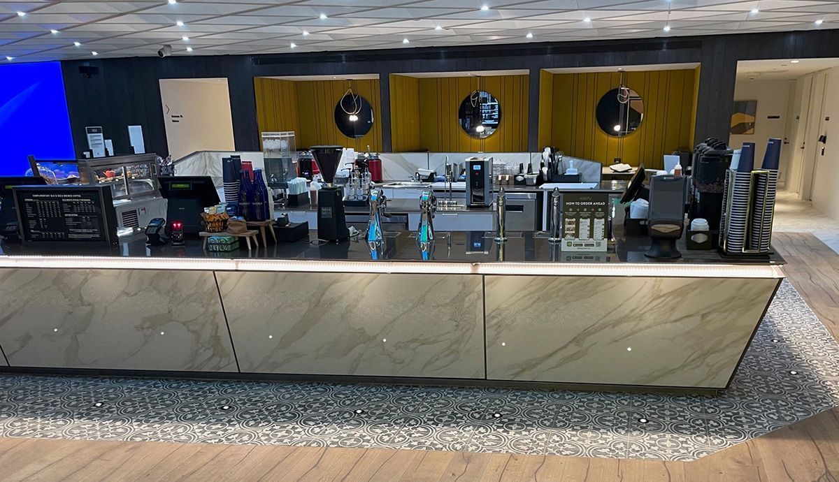 A large black counter in a restaurant with a lot of appliances on it