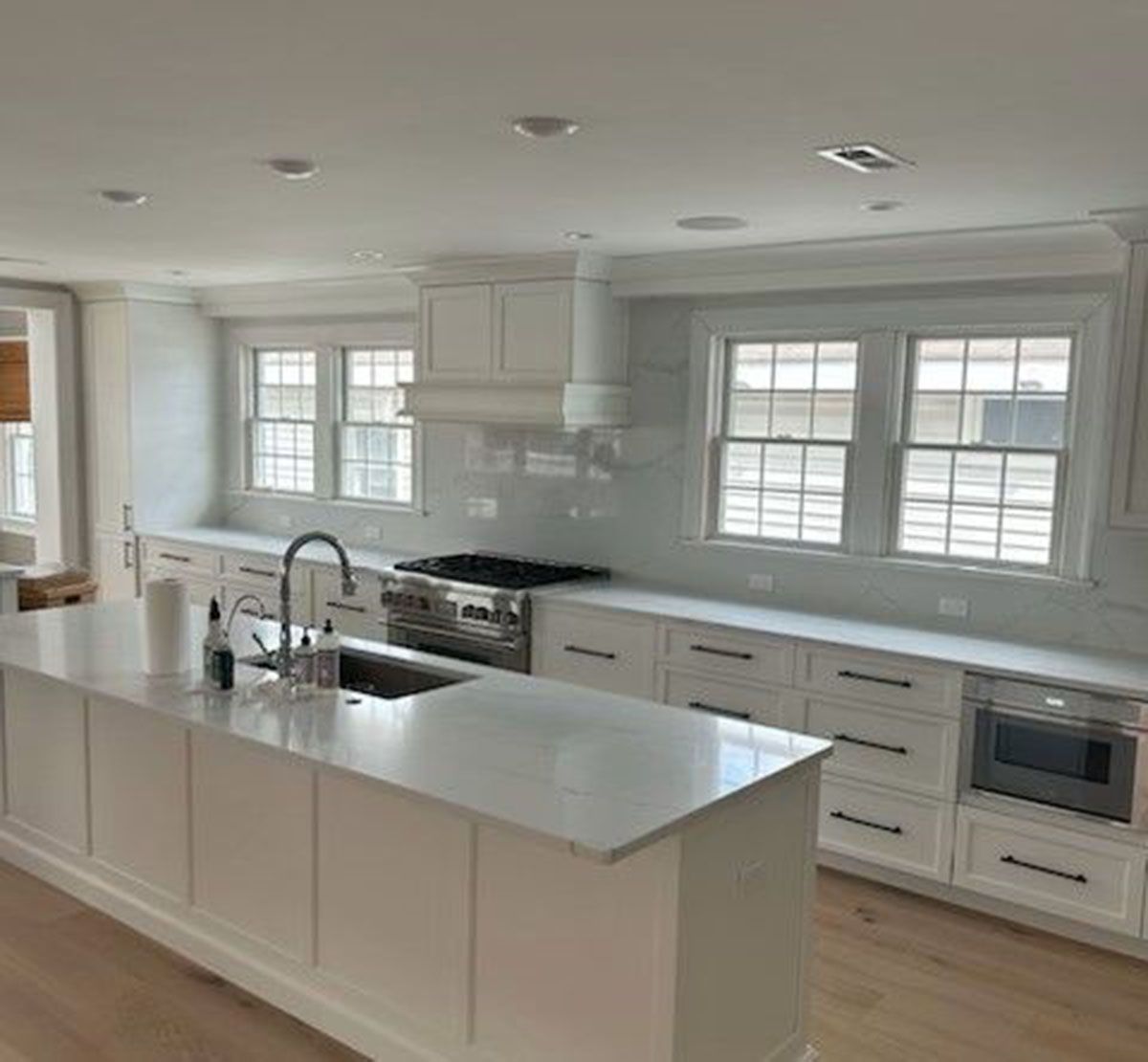 A kitchen with white cabinets, stainless steel appliances, a sink, and a large island