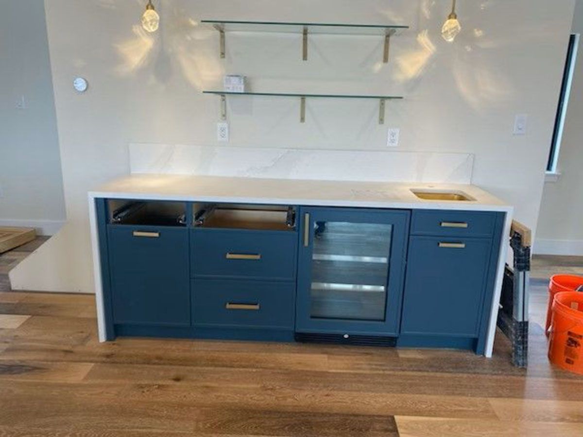 A large outdoor bar with a marble countertop and a flat-screen TV