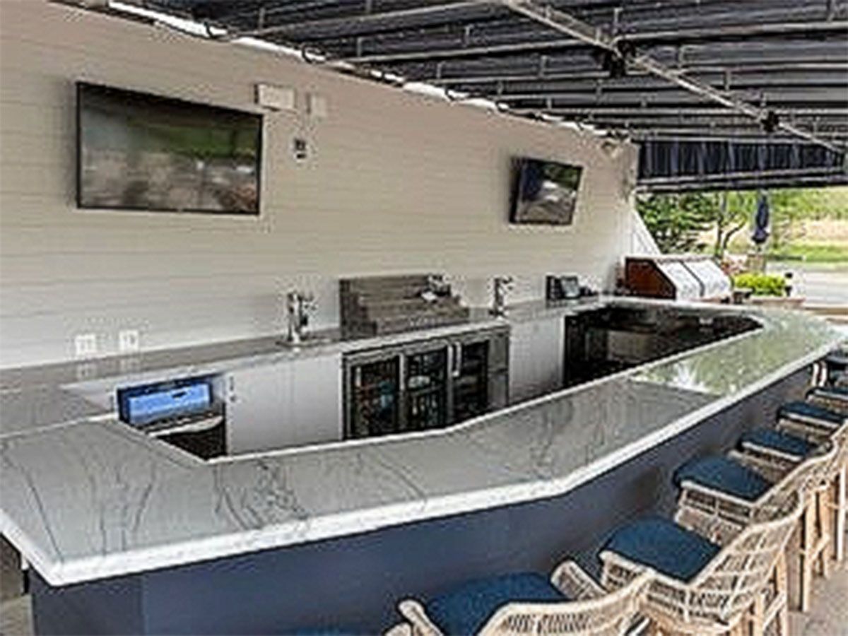 A large outdoor bar with a marble countertop and chairs