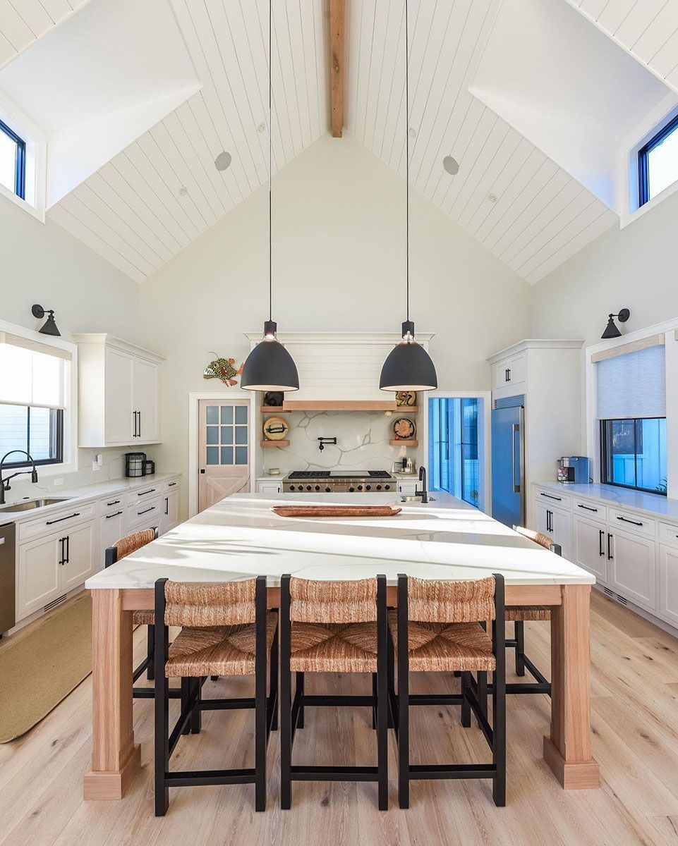 A kitchen with a large island and wicker chairs