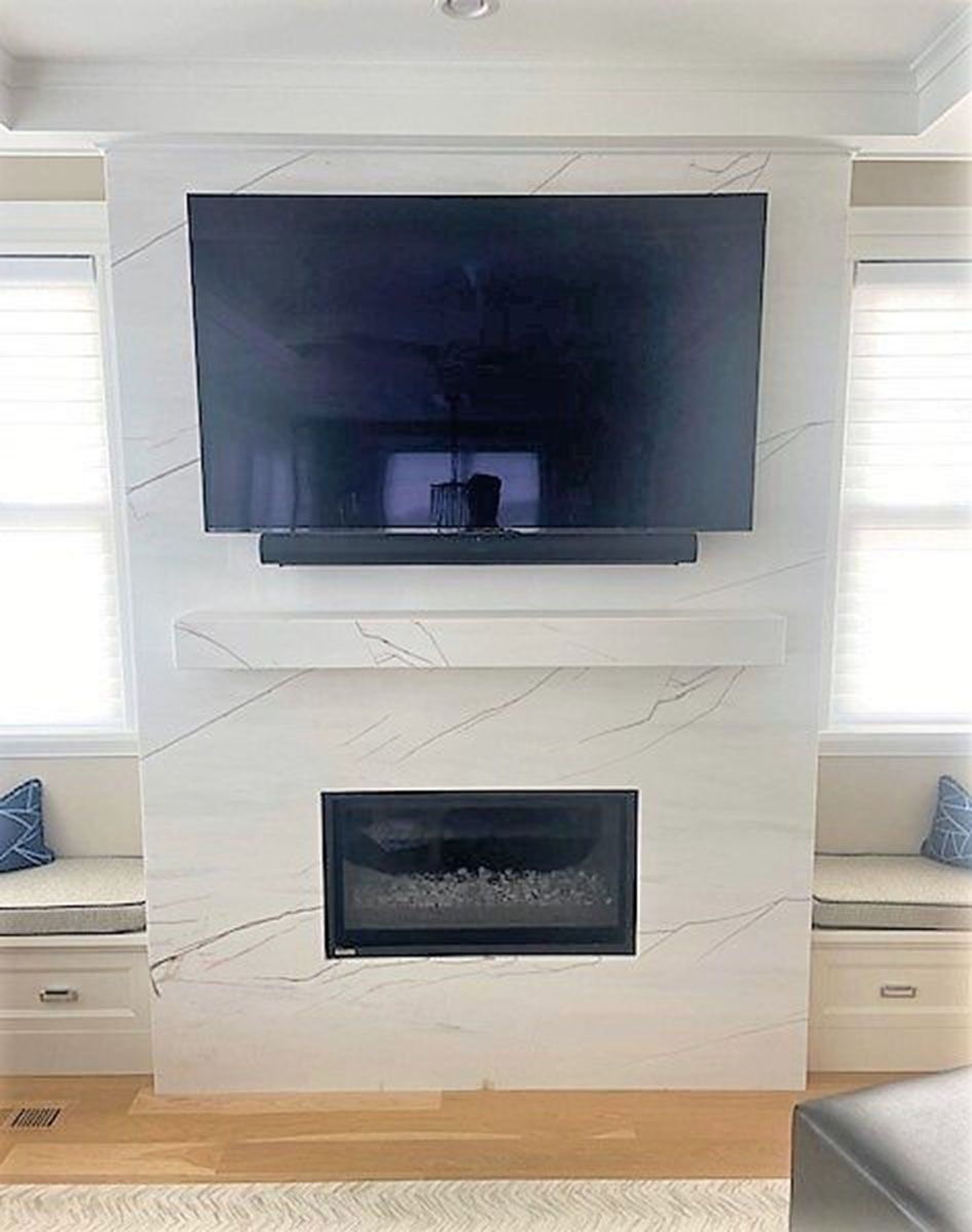 A living room with a fireplace and a flat-screen TV on the wall