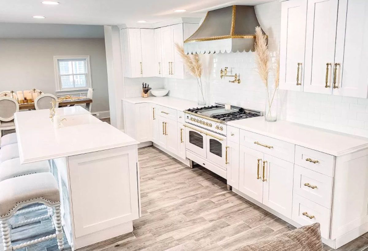 A kitchen with white cabinets, a stove, and a large island