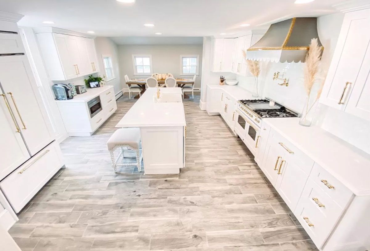 A kitchen with white cabinets, stainless steel appliances, and a large island