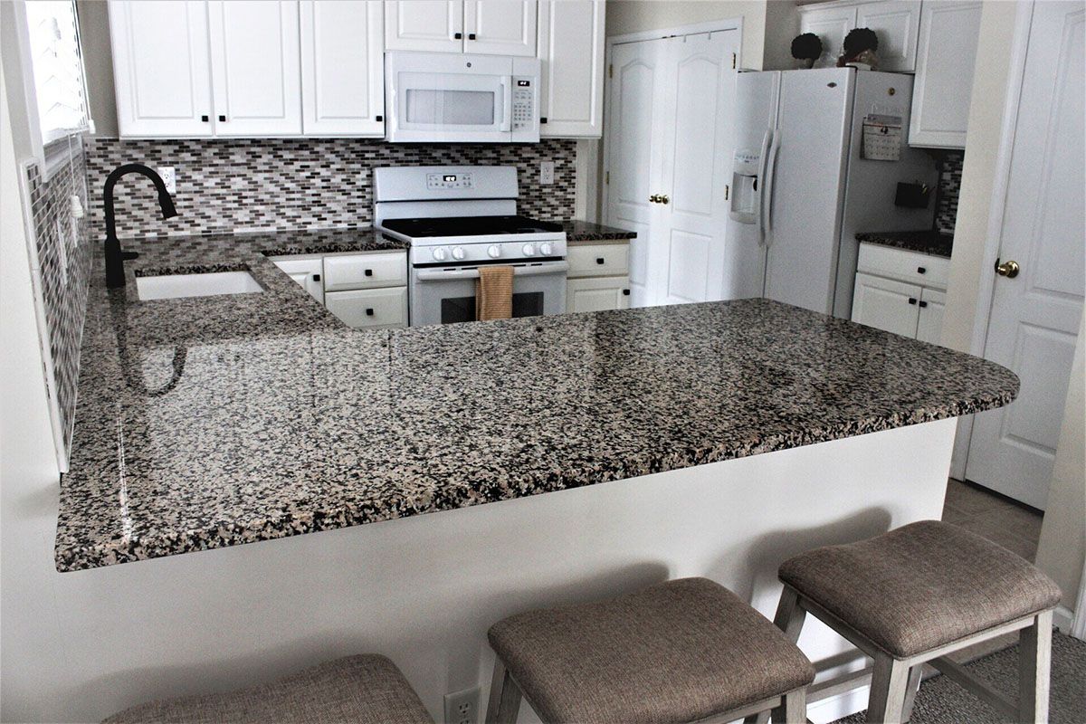 A kitchen with granite counter tops and white cabinets