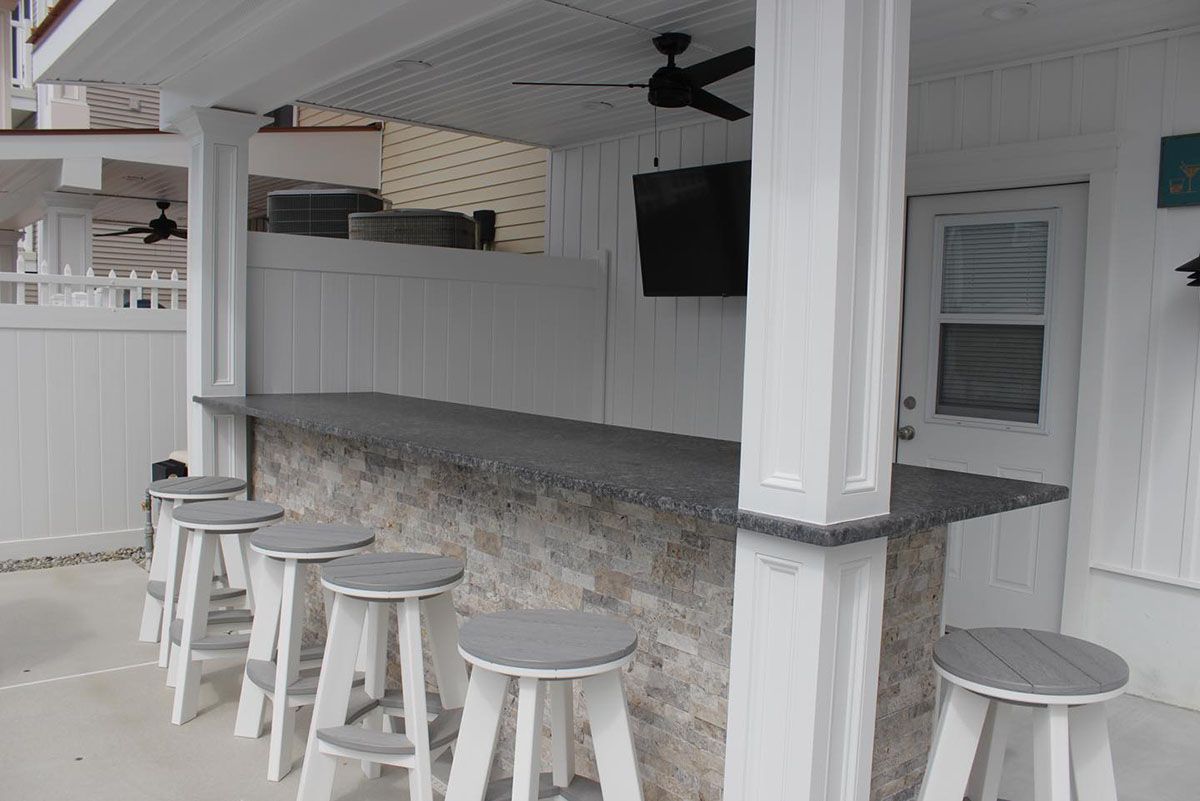 A patio with a bar and stools and a ceiling fan