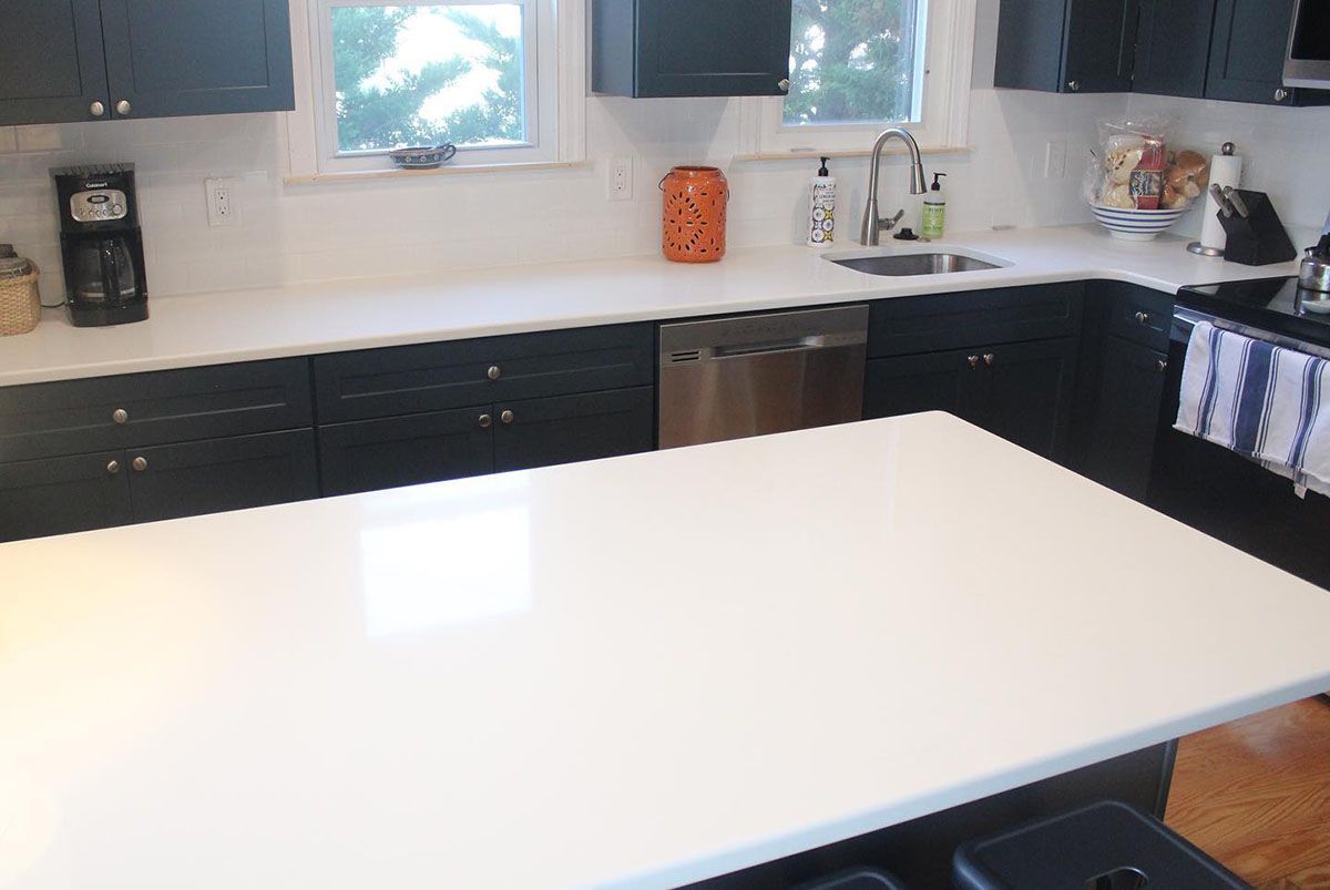 A kitchen with black cabinets and a white countertop