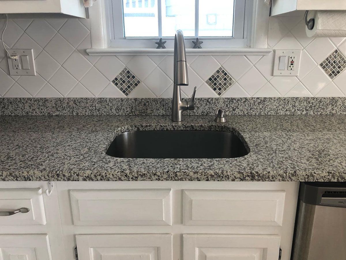 A kitchen sink with granite countertops and a faucet