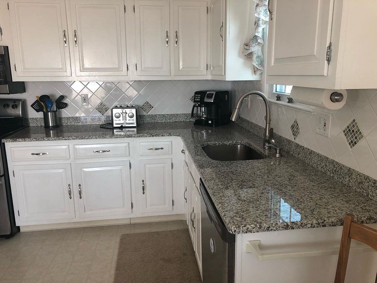 A kitchen with granite countertops and white cabinets