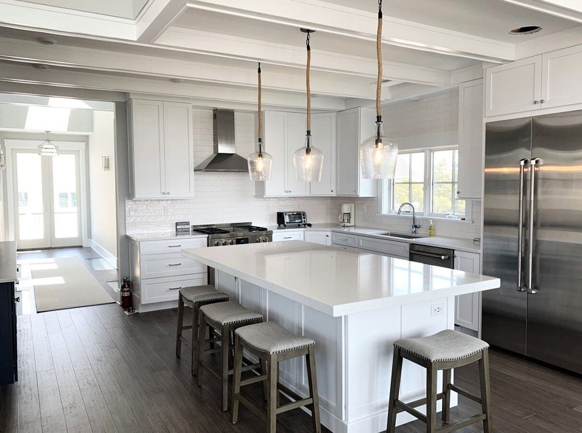 A kitchen with white cabinets, stainless steel appliances, a large island, and stools