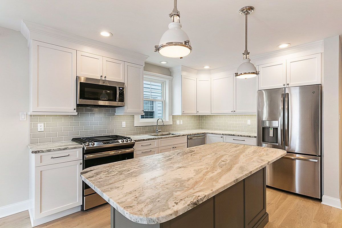 A kitchen with granite countertops, stainless steel appliances, and white cabinets