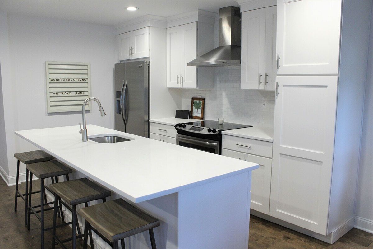 A kitchen with white cabinets, stainless steel appliances, and a large island